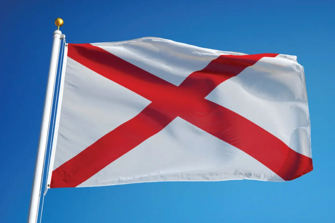 alabama flag waiving against a bright blue sky