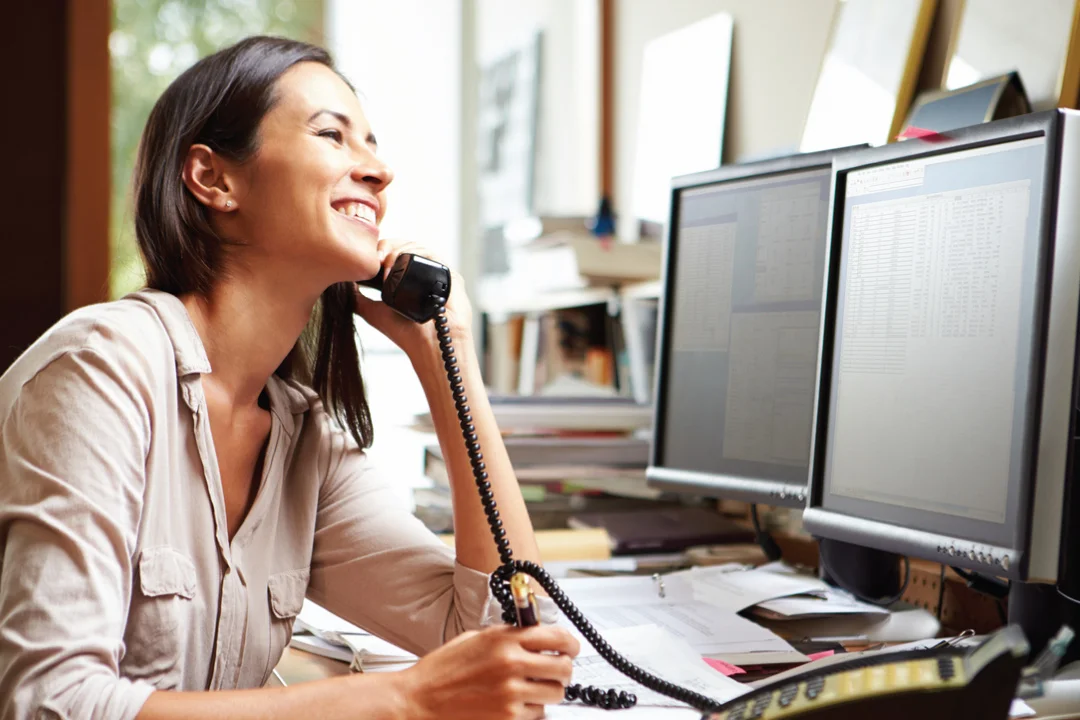 female loan professional sitting at desk smiling while on the phone