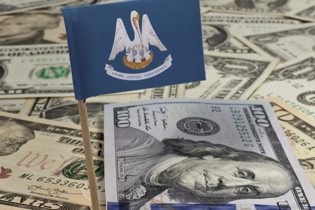 stack of 100 dollar bills with Louisiana flag in foreground