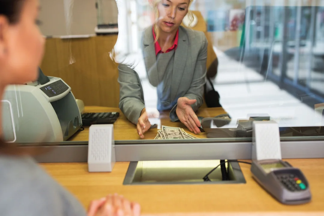 female loan provider counting out cash behind counter