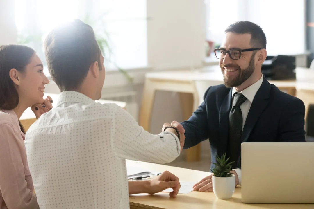 young couple sitting across from loan provider shaking hands